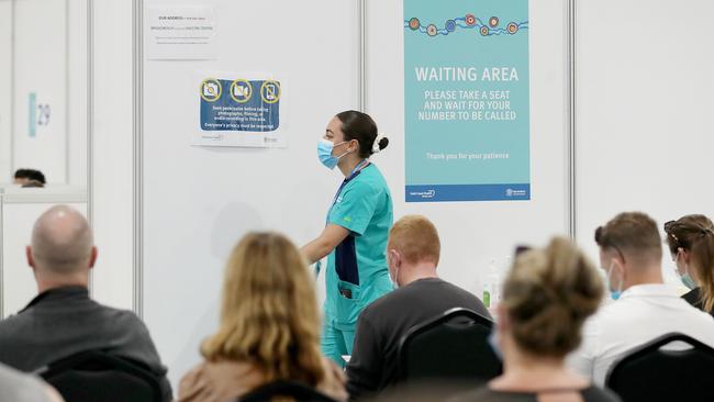 A staff member walks past a sign at a COVID 19 vaccination hub on the Gold Coast. Picture: NCA NewsWire /Jono Searle