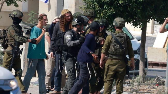 Israeli soldiers restrain Jewish settlers after they stormed the Palestinian West Bank village of Dayr Sharaf following the death of an Israeli man on November 2, 2023. Picture: Jaafar ASHTIYEH / AFP