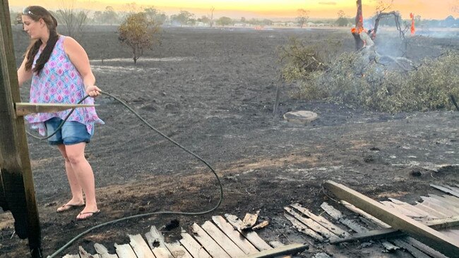 A Laidley resident dampens down parts of her property damaged in the bushfire.