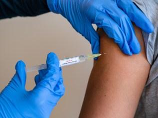 This picture depicts a young female clinician using a syringe to inject a concept COVD-19 liquid vaccine into a young girl patient during the Phase 3 vaccination human trials.