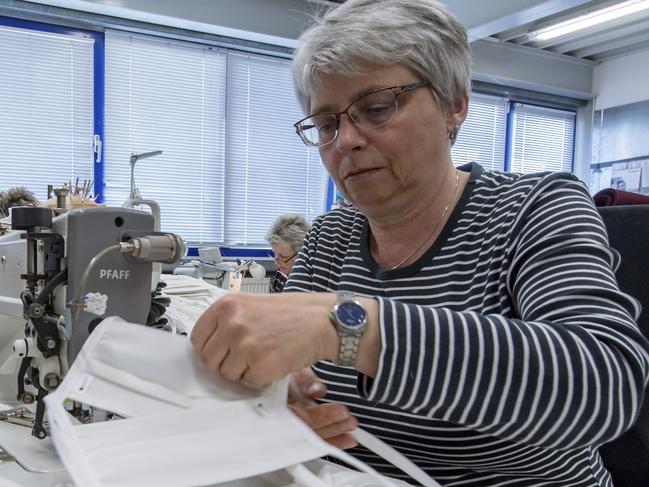 An employee of the textile company Br'ndl in Geyer, Germany sews face masks Tuesday, March 24, 2020. The masks are made of an antibacterial fabric in which threads of pure silver are woven. With this innovative technical textile, the company from the Erzgebirge Mountains has been fighting against hospital germs for a long time. What was previously too expensive for many hospitals is becoming interesting in the new coronavirus crisis. The company is now switching to face masks and protective clothing. For most people, the new coronavirus causes mild or moderate symptoms, such as fever and cough that clear up in two to three weeks. For some, especially older adults and people with existing health problems, it can cause more severe illness, including pneumonia and death. (Hendrik Schmidt/dpa-Zentralbild via AP)