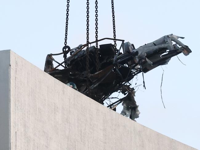 A large crane lifts the wreckage of a Robinson R44 helicopter off the roof top of the Double Tree Hilton hotel into a skip bin, before lowering it to the Cairns Esplanade. The chopper was stolen from Nautilus Aviation and crashed onto the roof at about 1:50am on Monday. Picture: Brendan Radke