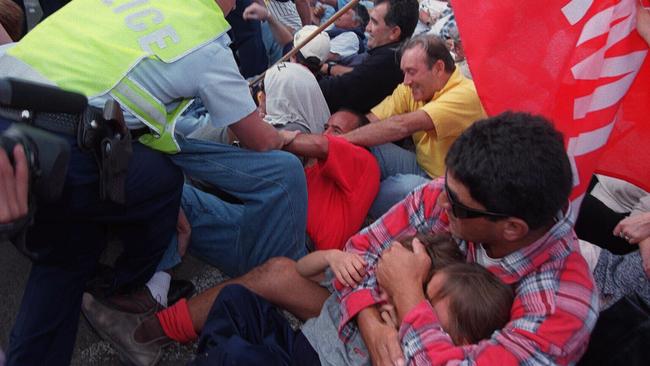 MUA member Thomas Mitchell shields daughters Nikita and Haley as police move in on the picket line at Botany Bay.