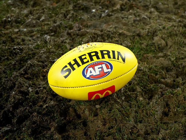 GEELONG, AUSTRALIA - JULY 20: The yellow Sherrin football is seen in mud during the 2024 AFL Round 19 match between the Geelong Cats and the Western Bulldogs at GMHBA Stadium on July 20, 2024 in Geelong, Australia. (Photo by Michael Willson/AFL Photos via Getty Images)