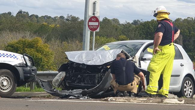 Firefighters inspect the crumpled car as traffic is diverted.