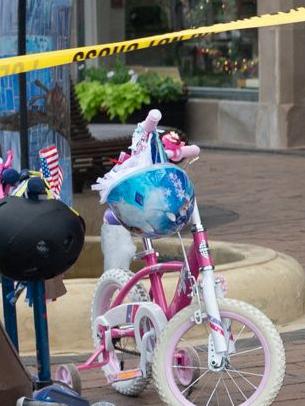 Police crime tape is seen around the area where children's bicycles and baby strollers stand near the scene.