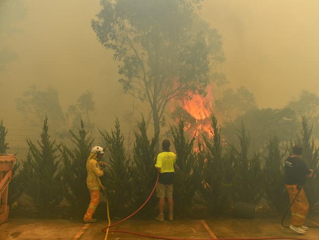 Workers trying to put out a bushfire behind a row of factories near West Queenbeyan. Picture: Mick Tsikas