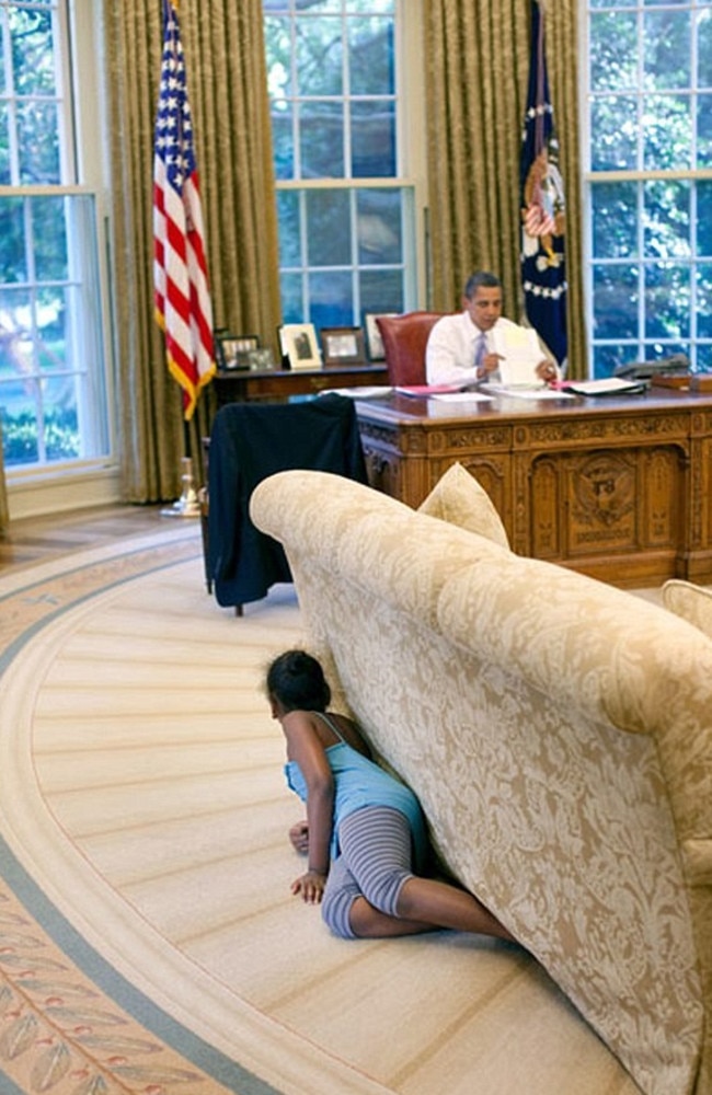 President Barack Obama’s daughter Sasha hides behind the sofa as she sneaks up on him at the end of the day in the Oval Office on August 5, 2009. Picture: Pete Souza/The White House