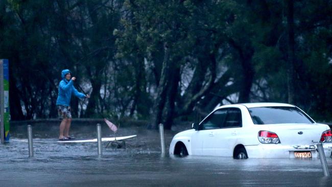 A person on a paddle board on flooded Goodwin St, near Narrabeen Lagoon, in February, 2020. Picture: Damian Shaw