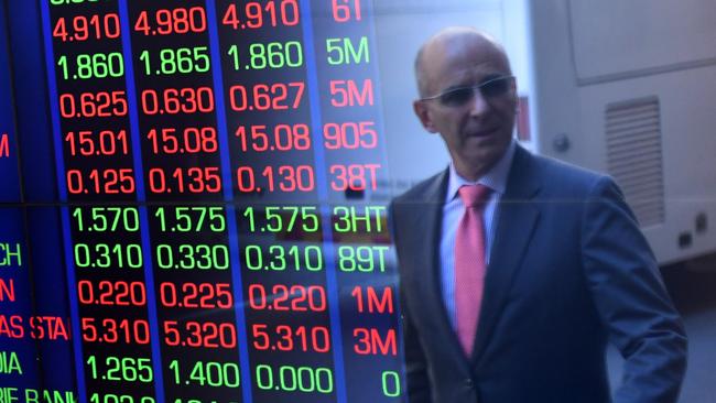 A businessman walks past the Australian Securities Exchange, where stock boards are flashing red amid the market slump.