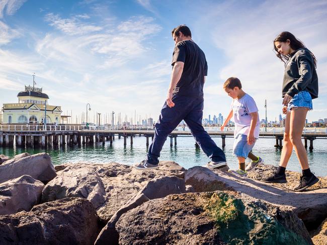 Peter with kids Ari, 7, and Eva, 13, climb on the rocks that make up the breakwater at St Kilda Pier. Picture: Jake Nowakowski