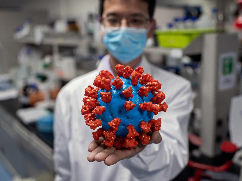 An engineer holds a model of the virus in Beijing. Picture: NICOLAS ASFOURI / AFP.