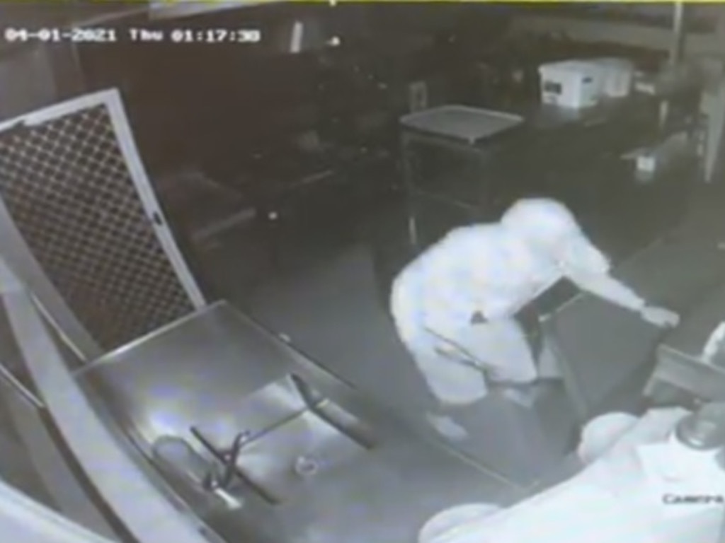 A thief searches the kitchen cupboards in view of CCTV.