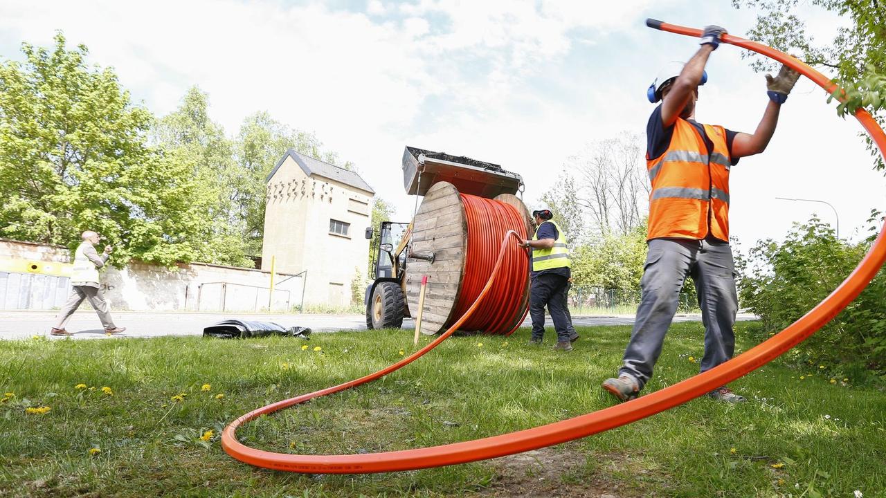 Workers unspool high-speed internet cable.