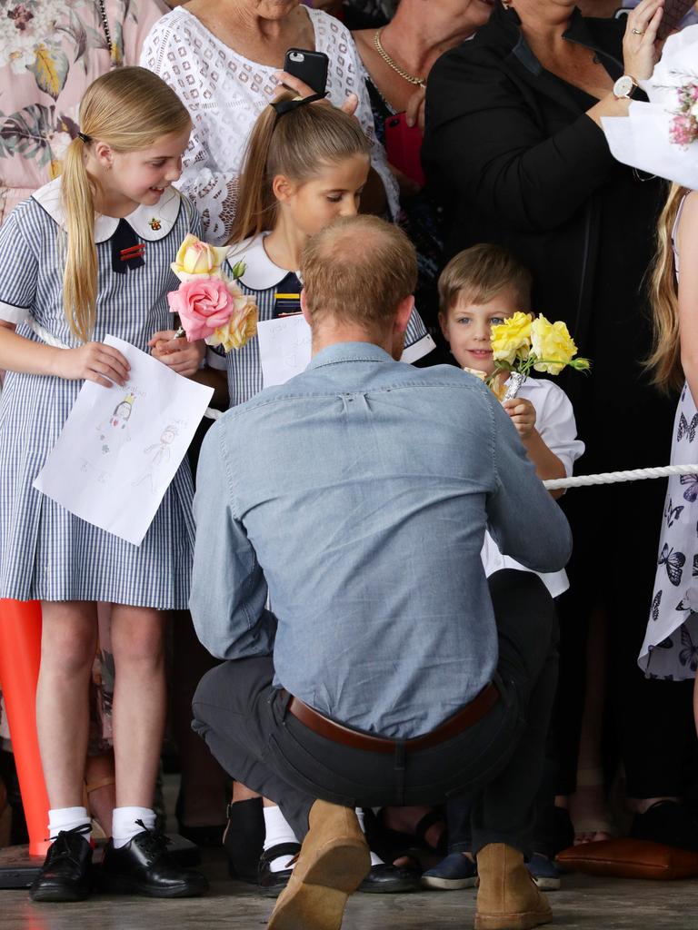 A young boy gives Prince Harry some flowers.