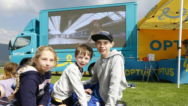 Leona, 9, left, Noah, 5, and Kohen Gilliland, 10, watching a movie on the big screen outside the evacuation centre for the fire ravaged Huon Valley. Picture: MATT THOMPSON