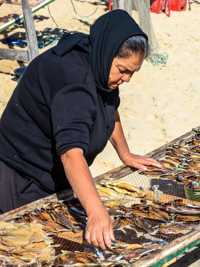 A Nazare woman arranges fish to dry on wire boards in the sun. Picture: Emily McAuliffe