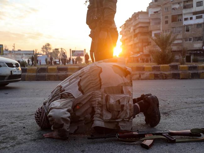 A Syrian anti-government fighter kneels to pray upon entering the west-central city of Hama. Picture: AFP