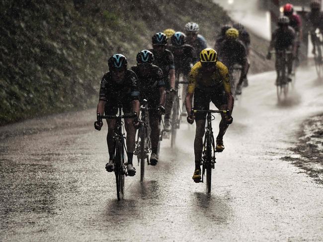 Great Britain's Chris Froome (R), wearing the overall leader's yellow jersey, rides in the rain. Pic: AFP