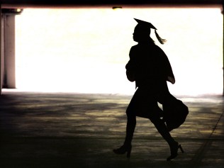 A late arrival makes her way quickly through the parking area under Ohio University's Convocation/Center  Jun 12, 1999.    (AP photo/Bill/Graham) silhouette education student graduate gown mortar board o/seas usa generic
