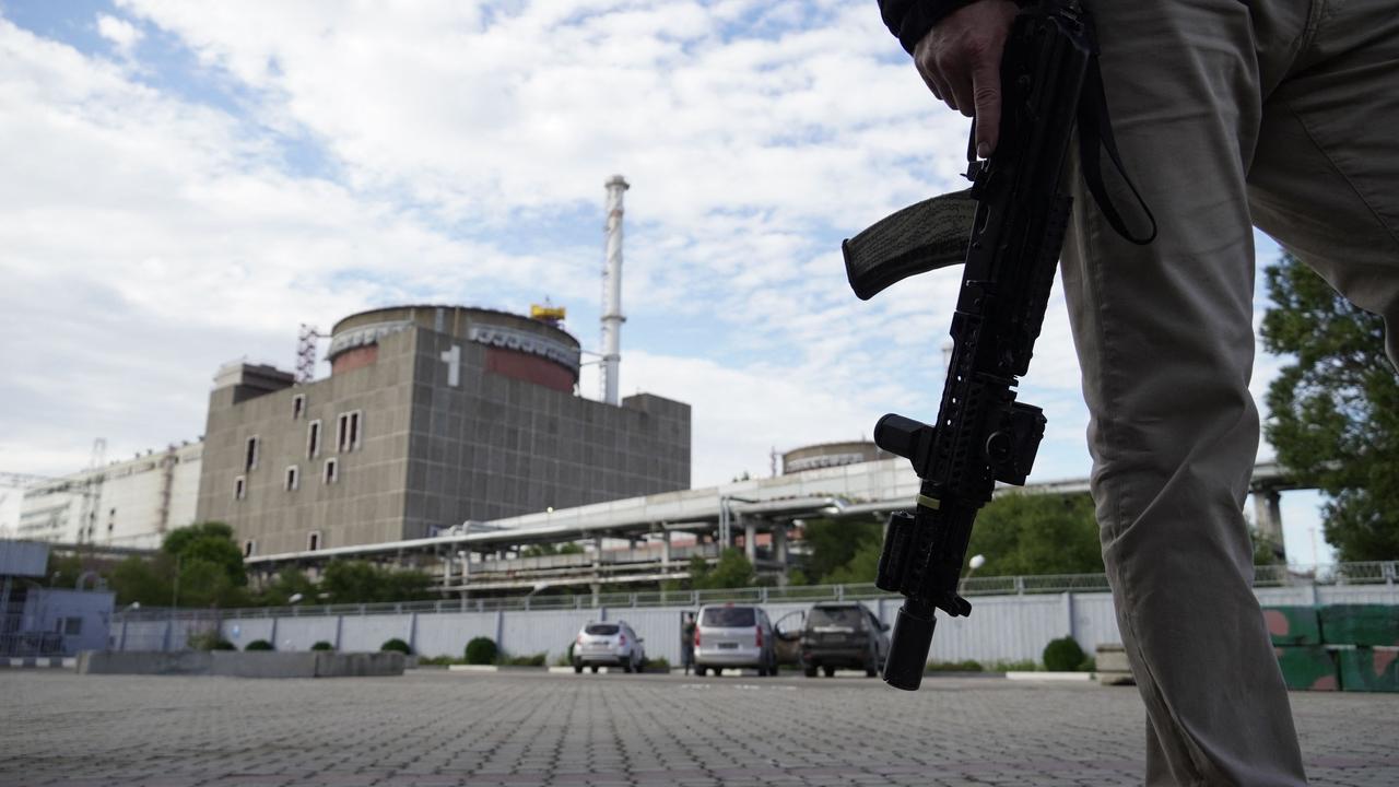 (FILES) This file photo taken on September 11, 2022 shows a security person standing in front of the Zaporizhzhia Nuclear Power Plant in Enerhodar (Energodar), Zaporizhzhia Oblast, amid the ongoing Russian military action in Ukraine. - Russian President Vladimir Putin on October 5 ordered his government to take over operations at Europe's largest nuclear power station in the Russia-annexed region of Zaporizhzhia in southern Ukraine. (Photo by STRINGER / AFP)