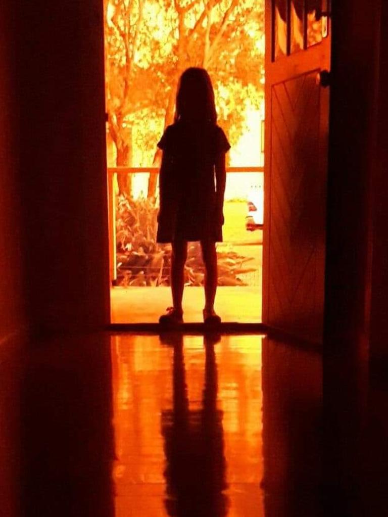 Ava Dixon looks out at a fire front approaching her house near Port Macquarie. Picture: Robert Dixon.