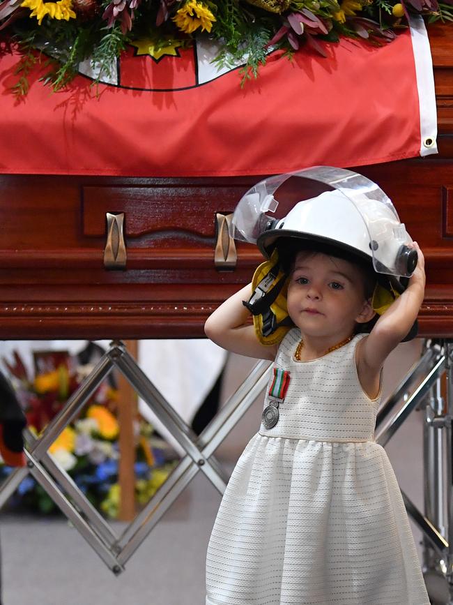 Charlotte O'Dwyer stands in front of her father’s casket wearing his helmet. Picture: AAP Image/Dean Lewins