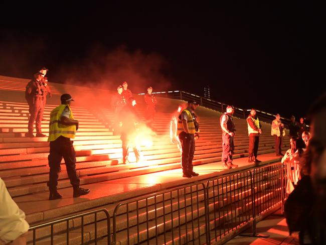 Police stand against the crowd at the Opera House forecourt as flares are thrown on Monday night. Picture: NCA NewsWire / Jeremy Piper