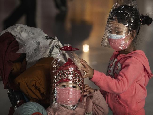 Children sport water cooler bottles over their heads at Beijing Picture: Getty Images