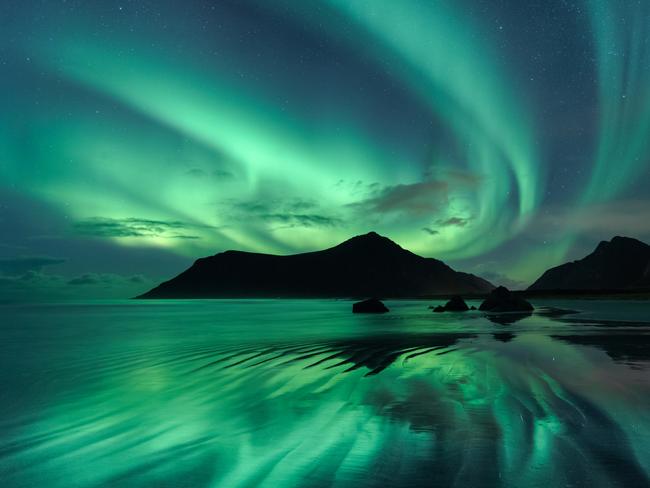 Insight Astronomy Photographer of the Year 2017 shortlist selection:   Reflection © Beate Behnke (Germany)The reflection in the wave ripples of Skagsanden beach mirrors the brilliant green whirls of the Aurora Borealis in the night sky overhead. To obtain the effect of the shiny surface, the photographer had to stand in the wave zone of the incoming flood, and only when the water receded very low did the opportunity to capture the beautiful scene occur.Skagsanden, Lofoten, Norway, 28 October 2016