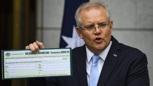 Scott Morrison holds up a Coronavirus Isolation Declaration Card on Friday. Picture: AAP