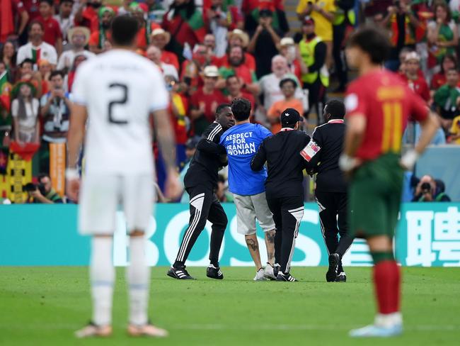 Security guards march the pitch invader away. Picture: Justin Setterfield/Getty Images