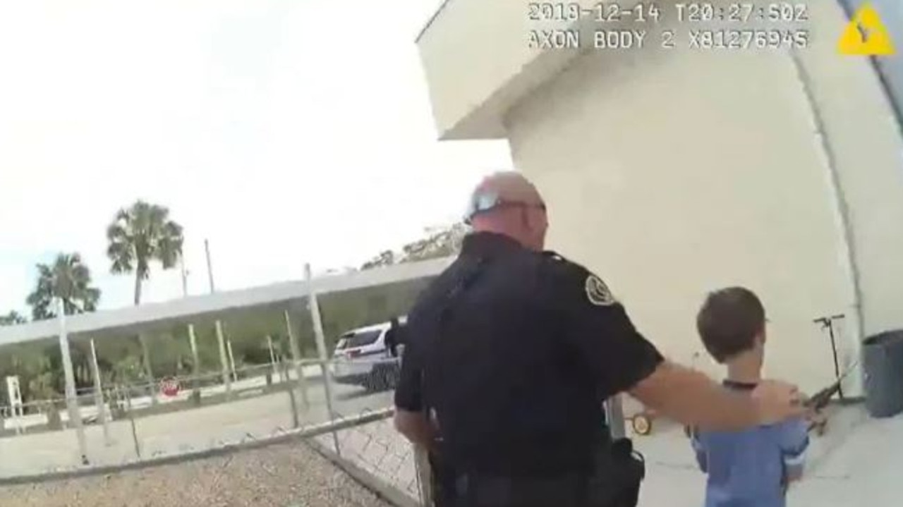 An officer walks the cuffed boy to the police car. Picture: KWPD