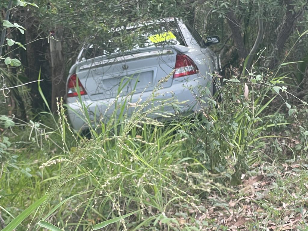 The white Commodore slid off the road and into an embankment with the trees and shrubbery stopping the vehicle from plummeting any further.