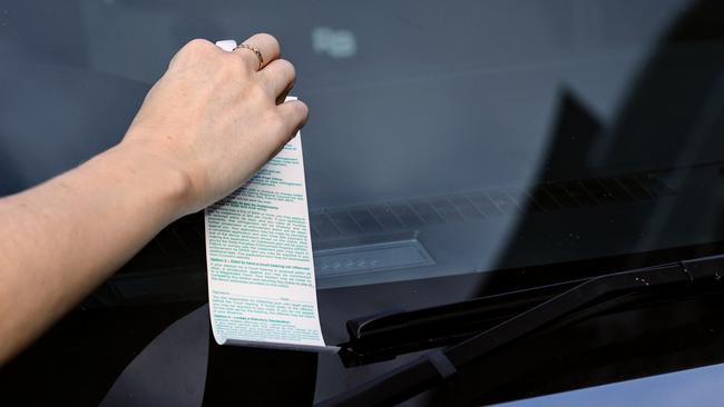 A Cairns city office worker removes a parking fine from her car after parking for too long in the CBD. Picture: Brendan Radke