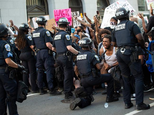 A man screams with emotion as he sees a policeman take a knee while hundreds protest the death of George Floyd next to the White House. Picture: AFP