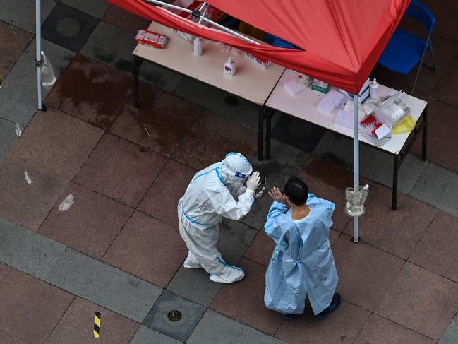 A health worker wearing personal protective equipment scans a code for a PCR test during lockdown in the Jing'an district in Shanghai. Picture: AFP