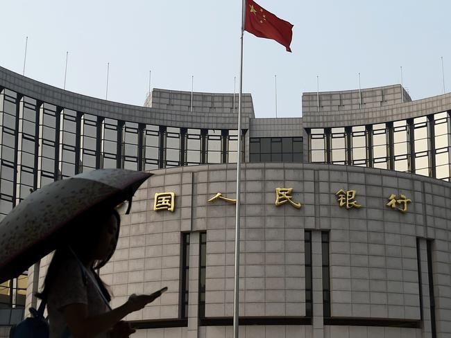 (FILES) This file photo taken on July 8, 2015 shows a pedestrian walking past the People's Bank of China, the central bank of China, in Beijing. China's central bank on August 25, 2015 cut its benchmark interest rates and the amount of cash banks must keep on hand, the latest stimulus aimed at boosting the world's second-largest economy as it battles a collapse in share prices. AFP PHOTO / FILES / GREG BAKER