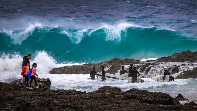 Surfers enter rough surf at Snapper Rocks on the Gold Coast on Thursday. Picture: Nigel Hallett