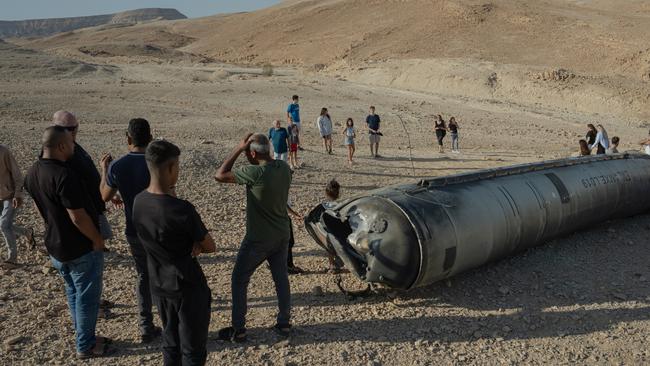 People stand near the remains of a missile on October 2 near the Dead Sea, Israel. Picture: Erik Marmor/Getty Images