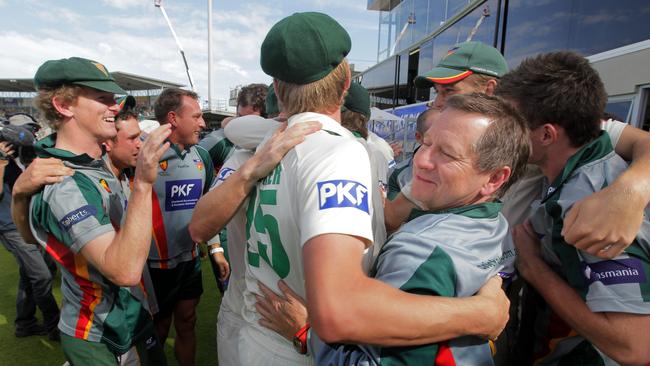 Tigers' captain George Bailey watches on, left, as allrounder James Faulkner celebrates with coach Tim Coyle.