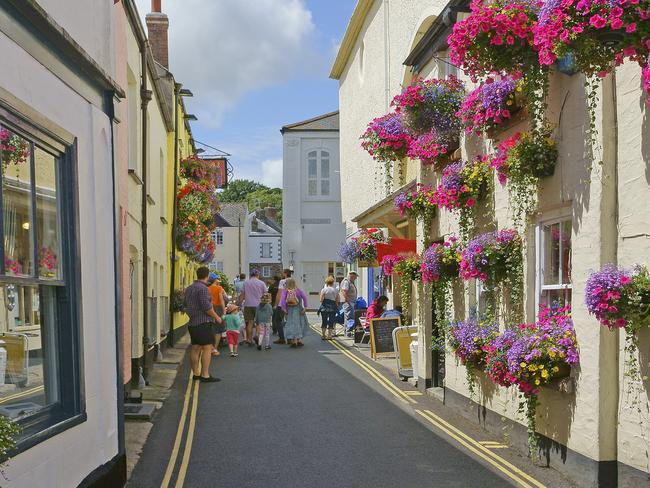 ESCAPE:  Beautiful floral display of hanging baskets and window boxes on the buildings in the narrow streets of Fowey, Cornwall, England, UK Picture: Istock