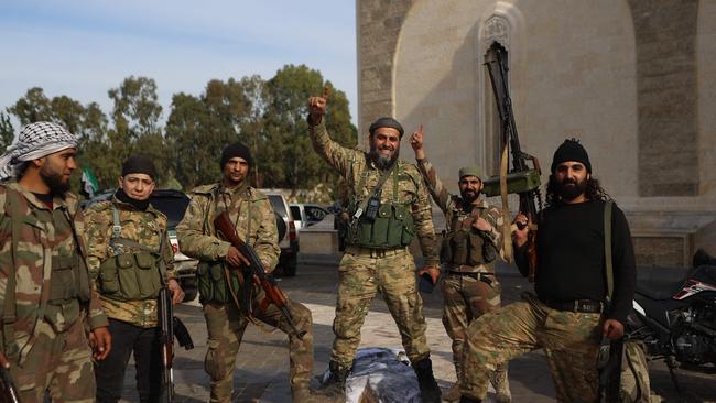 Rebel fighters pose for a picture outside the mausoleum of Syria's late president Hafez al-Assad in the family's ancestral village of Qardaha in the western Latakia province on December 11. Picture: AAREF WATAD/AFP