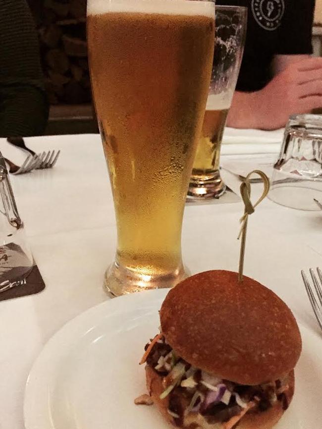 Slow cooked and smoked beef cheek slider with creamy slaw and spicy barbecue sauce, accompanied by Akasha’s Tradewind lager.