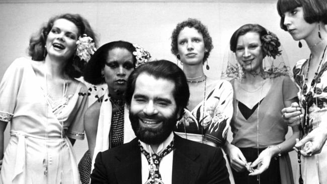 FILE -- In this Nov. 29, 1973 photo German fashion designer Karl Lagerfeld, left, poses with models in Krefeld, Germany. Chanel's iconic couturier, Karl Lagerfeld, whose accomplished designs as well as trademark white ponytail, high starched collars and dark enigmatic glasses dominated high fashion for the last 50 years, has died. He was around 85 years old. (Willi Bertram/dpa via AP, file)