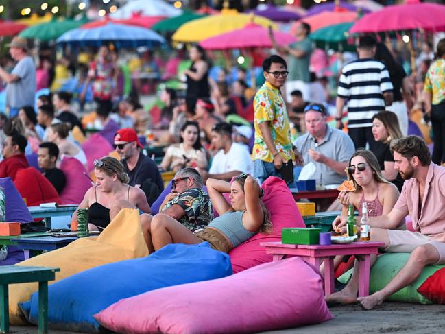 Foreign tourists relax on the Kuta Beach near Denpasar on Indonesia's resort island of Bali on November 18, 2023. (Photo by SONNY TUMBELAKA / AFP)