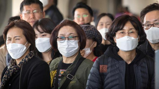 Passengers wear face masks to protect against the spread of the Coronavirus as they arrive on a flight from Asia at Los Angeles International Airport this week. Picture: AFP.