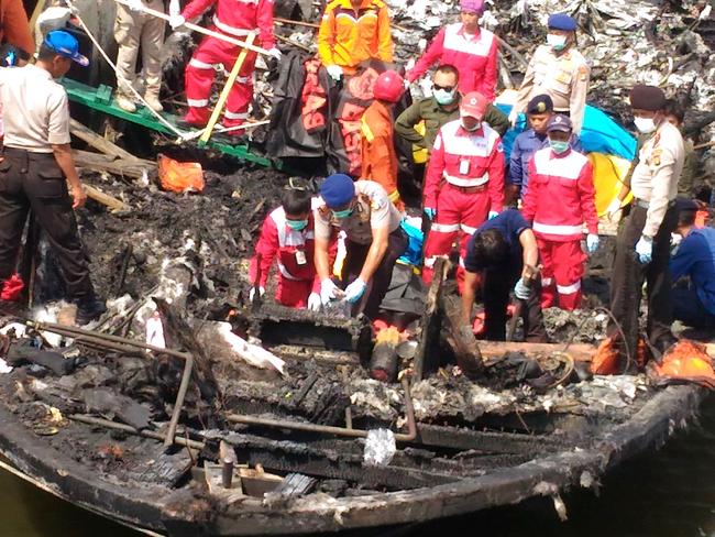 Rescuers search the charred passenger boat which was ferrying around 200 people off the coast of Jakarta to Tidung island, a tourist destination 50 kilometres (30 miles) from the capital when a fire started on January 1, 2017. At least 23 people have been killed and 17 are missing after a passenger boat caught fire near Jakarta, according to officials. / AFP PHOTO / DYAHFRAGMA