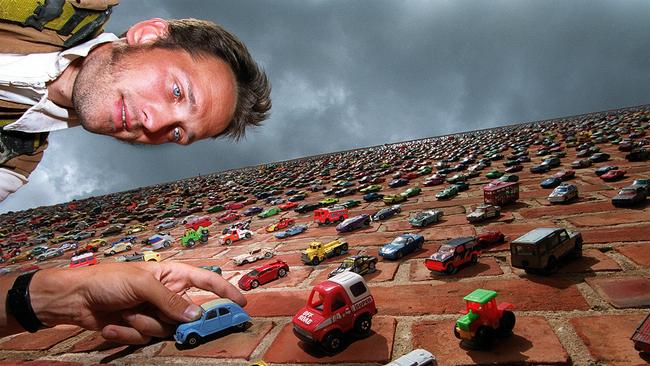 Slovenian artist Matej Vogricic with the brick wall covered in almost 15,000 mini toy cars in 2000.