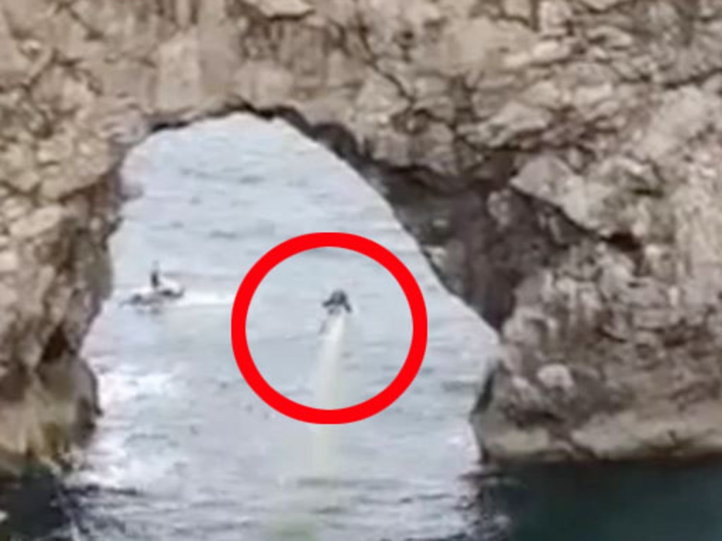 A daredevil used a jet pack to fly under the arch at Durdle Door, UK.